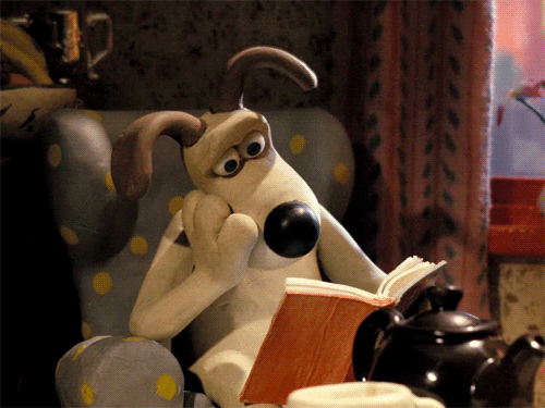 Gromit sitting in chair reading book.