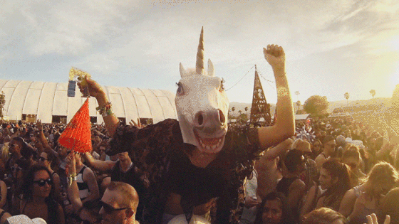 Person with unicorn mask in crowd fist pumping.