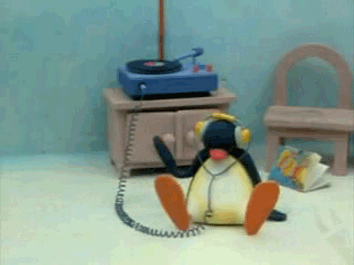Penguin sitting on floor with headphones on while moving arms to music