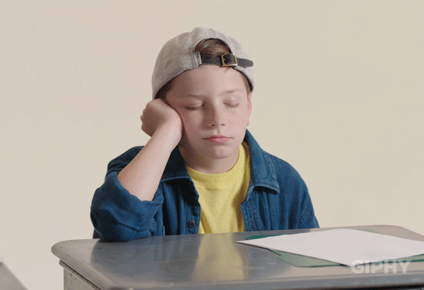School boy rests his head on his hand while falling asleep