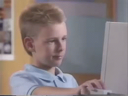 Child at computer giving thumbs up sign