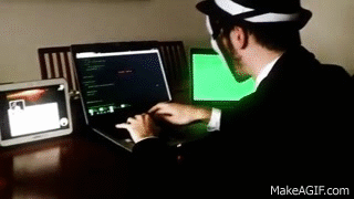 homem com máscara do Anonymous, famoso grupo de hackers, usando computadores para cometer crimes cibernéticos