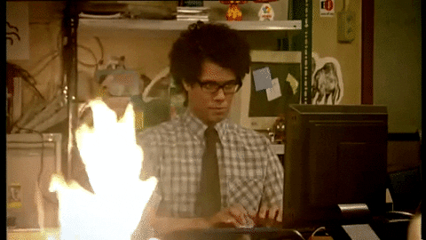 Um homem negro digita em um computador enquanto uma fogueira arde ao seu lado.