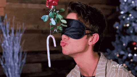Blindfolded woman trying to kiss a hanging candy cane