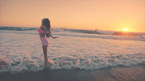 A little girl standing in the ocean at sunset, celebrating her Quinceanera