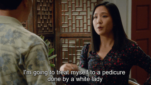 An asian woman fanning herself and saying 