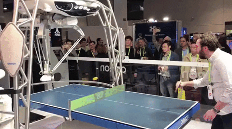 man playing ping pong with a robot 