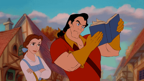 Una gif dalla fiaba "La Bella e La Bestia", dove Gaston prova a leggere un libro in verticale e Belle, a braccia conserte, scuote il capo e lo biasima.