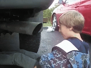 Kid staring into exhaust pipe gets a face full of fumes GIF