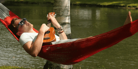 Man playing ukulele while relaxing on a hammock 