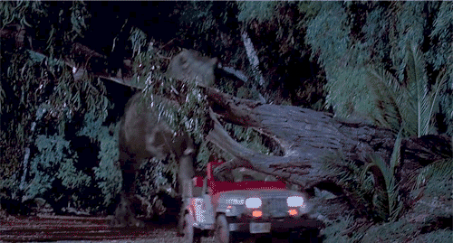 Gif from the movie Jurassic Park showing a T-rex crashing through a large tree as it chases a Jeep.