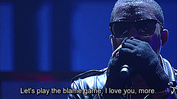 Kanye West singing Blame Game with a blue background, wearing sunglasses and gloves.