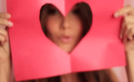 beautiful woman blows a kiss through a heart