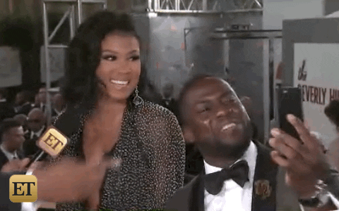 gif of Kevin Hart waving at his phone during a video call while he is in an event
