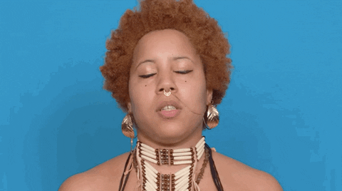 a girl with an afro closing her eyes against a blue backdrop