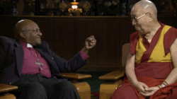 gif animé du dalai lama en train de prendre la main d'un prêtre avec tendresse et sourire