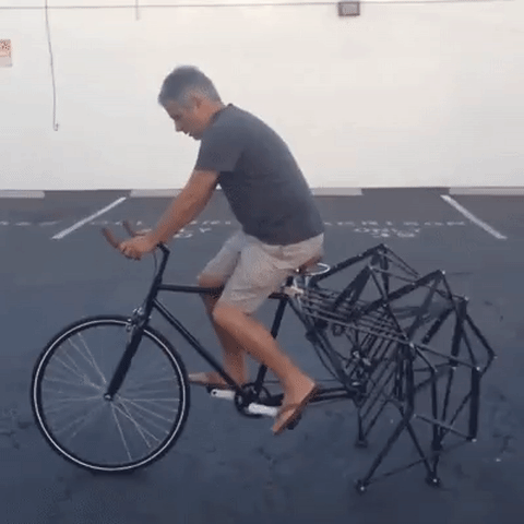 Man cycling a weird bike with no back wheel, but a mechanical structure instead.