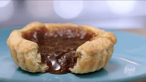 Butter tarts — their saccharine filling punctuated with pop of raisins and offset by the thick flake of their crust — taste to me like Christmas. Of course, nobody makes them better than my mum, who always smiles slyly as she feeds them to me for breakfast (“Is it Christmas?”) alongside my coffee. Little known outside of Canada, my mum takes pride in butter tarts’ quintessential Canadian-ness. Last year, because of the pandemic, I was unable to make it home for the holidays so I was glad that I had copied out her recipe, which comes from an issue of Saveur from March 2000. I made two dozen (warning: this recipe makes a big batch) during a virtual baking session with my mum, and proceeded to eat them all, unaided by my (supposedly) sweet adverse partner. 

I recently learned more about the story behind the dessert I’ve enjoyed for so long. I should not have been surprised, given the gender dynamics of ‘traditional’ cooking and Canada’s colonial history, to discover butter tarts’ links to colonialism and patriarchy. Butter tarts, it turns out, were invented by the Filles Du Roi, young women sent to Canada between 1663 and 1673 by Louis XIV to marry, cook, clean, and procreate in support of France’s efforts to colonize New France. These women, faced with the limited resources of their new lives on the ‘frontier’, developed the butter tart out of simple and readily available ingredients.

This year, I’m lucky enough to be able be home for the holidays again and I’m very excited to indulge in (far too many) of my mum’s butter tarts. As I savor the gooeyness, I will be reflecting on this history and marveling at the rich stories hidden in the mundane all around us — and especially in what we eat. Butter tarts are an edible reminder of the intimate links between food and national identity and of the importance of interrogating these identities and the often exploitative, violent, and exclusionary histories that underlie them. Interrogating ‘Canadianness’ requires reckoning with this country’s abhorrent history of colonialism. The story of the Filles Du Roi forces us to furthermore think about the intricate ways in which the patriarchy and colonialism intersect to blur the lines between victim and perpetrator; these women were both the victims of a patriarchal system that exploited their reproductive labour for the glory of a monarch and perpetrators of a violent and racist campaign of dispossession. I don’t think this will temper their sweetness but perhaps it will make it more complex. 