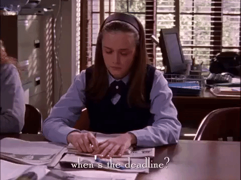 Rory Gilmore, character from the Gilmore Girls, is sitting at a desk in her classroom. She has books and papers scattered on her desk, as she asks: "When's the deadline?"