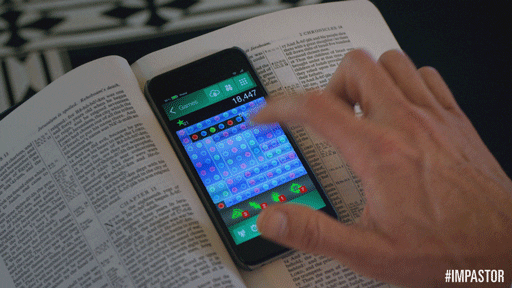 Person playing a game on their phone while its resting on an open book