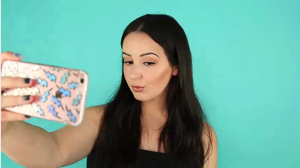 Dark haired woman snapping photos of herself seductively