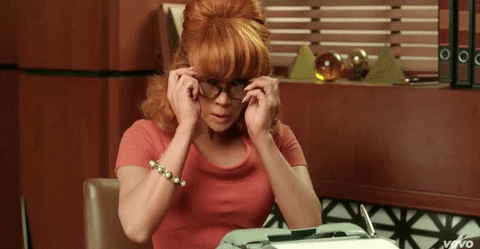 Jennifer Lopez dressed as a stenographer putting on her glasses