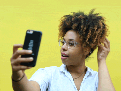 a GIF of a black girl playing with her while taking a selfie
