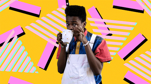 Young guy sipping tea against a bright multicoloured wall 