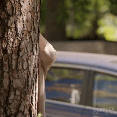 mulher com binóculos escondida atrás de uma árvore observando alguém