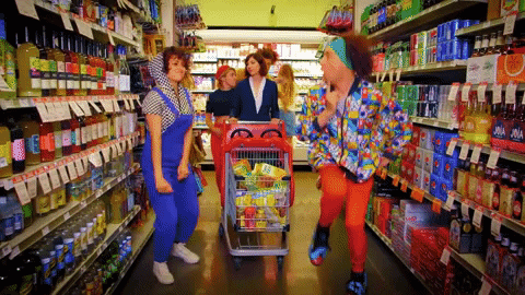 college friends dancing while shopping their things together in the supermarket