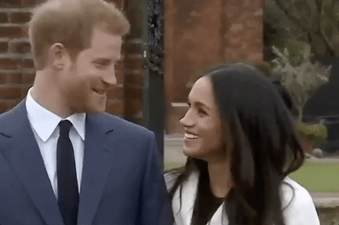 Meghan Markle and Prince Harry smiling and holding hands. 