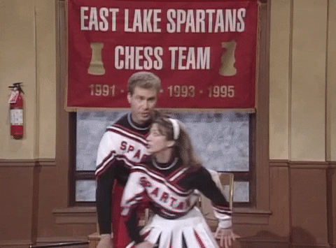 Guy and girl in red, white and black cheerleading outfits doing a silly move