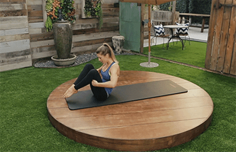 Mujer haciendo yoga sobre un tapete en su jardín