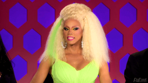 [Gif via Giphy description: Ru Paul with a cringing smile.]