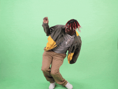A man dances in front of a greenscreen enthusiastically, then trips and knocks down the greenscreen.