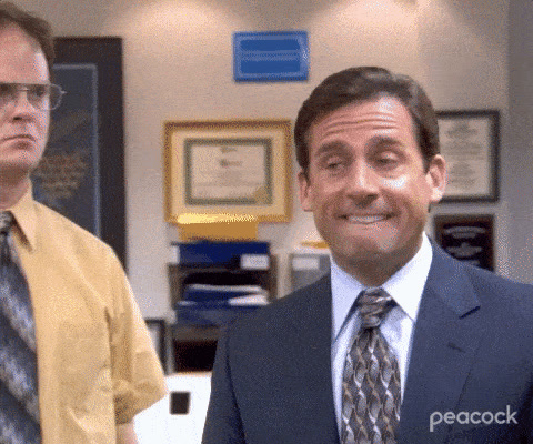 The Office: Michael Scott grimaces nervously while Dwight Schrute watches behind him.