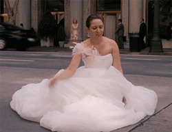 Maya Rudolf in a wedding dress signaling traffic to drive around her as she defecates in the street wearing a wedding dress