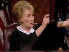 GIF of Judge Judy banging her hand on her podium and then tapping her watch