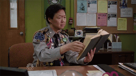 A GIF of a person smiling while reading a book