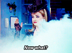 Sabrina in fancy witch clothes talking from behind a cloud of smoke.