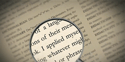 Il glossario aziendale viene rappresentato in senso figurativo con un dizionario aperto in cui vengono ricercate le parole con una lente di ingrandimento.