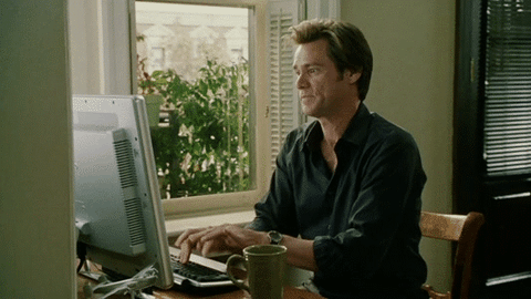 Jim Carey sitting at a desktop computer and typing furiously.