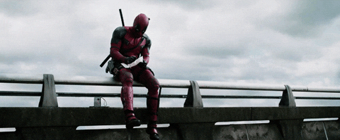 Marvel superhero, Deadpool, sitting on a guardrail and drawing.