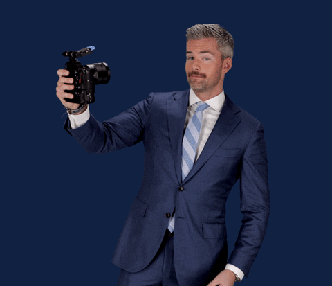 Man pointing to a video camera as he records himself.