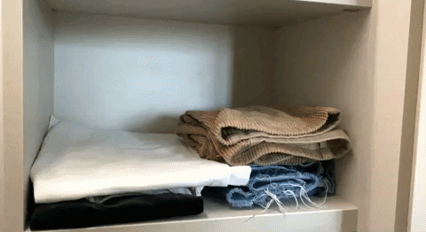 Gif of a folded up pair of jeans being placed on a shelf alongside other pairs of trousers