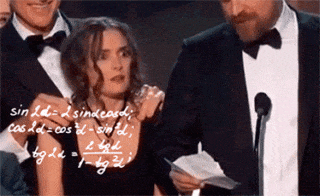 Gif of Winona Ryder, a white woman with a black dress, a necklace, and dark brown hair, looking around confused as white math equations appear around her, as she stands between two tall white men in black suits and bow-ties and white shirts