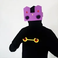Figure in black raising a purple faceted paper mask to the face
