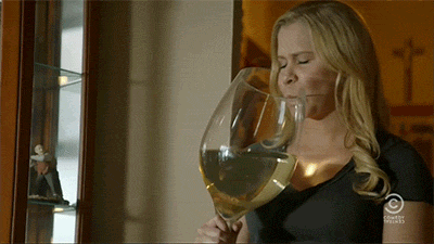ženska pije vino iz velikega kozarca