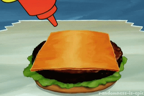 Ketchup is spread on top of a slice of cheese on a cheeseburger. The ketchup forms the shape of a heart.