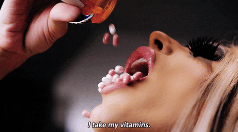Mujer volcando en su boca un tarro lleno de pastillas. 